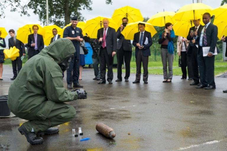 Les militaires du SEDEE montrent, durant une averse soutenue, comment identifier des munitions chimiques et comment les préparer pour le transport. 